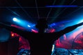 DJ in headphones waving his arms at party night club silhouette with colored light