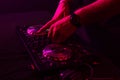 Dj mixing on turntables with color light effects. Soft focus on hand. Close-up.