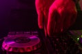 Dj mixing on turntables with color light effects. Soft focus on hand. Close-up.