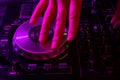 Dj mixing on turntables with color light effects. Soft focus on hand. Close-up.