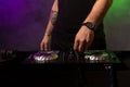 Dj mixing on turntables with color light effects. Soft focus on hand. Close-up.