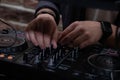 A DJ in a nightclub at the control panel adjusts the music. Music is playing, creating an atmosphere.