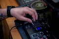 A DJ in a nightclub at the control panel adjusts the music. Music is playing, creating an atmosphere.