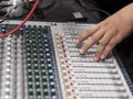 A DJ operates a 16 channel digital stereo mixer. Adjusting the channel faders