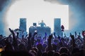 DJ performing for a crowd of party people with their hands in the air