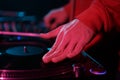 DJ scratching records on deck in night club. Hip hop disc jockey scratching vinyl disc on turntable in close up Royalty Free Stock Photo