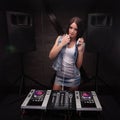 Dj with white headphones touching her lip with finger. Loudspeakers on background mixer on table