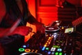 DJ working on a professional controller in a dimly lit room, with illuminated buttons