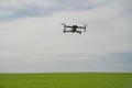 DJI drone hovers over a green field, light sky