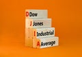 DJIA Dow Jones industrial average symbol. Concept words DJIA Dow Jones industrial average on wooden block on beautiful orange