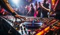 DJs hand adjusting music on turntable at club party with dancing crowd in the background vibrant nightlife scene Royalty Free Stock Photo