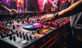 DJs hand adjusting music on turntable at club party with dancing crowd in the background vibrant nightlife scene Royalty Free Stock Photo