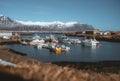 Djupivogur fishing village full of colorful boats in Iceland. Winter scenery with snow capped mountains.