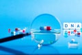 DNA pill on the background of a laboratory table with medicines and preparations. View through a magnifying glass. On a blue Royalty Free Stock Photo