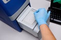 Dna test in the lab. the technician inserts the test tubes into the dna analyzer. Gloved hands close up