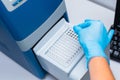 Dna test in the lab. the technician inserts the test tubes into the dna analyzer. Gloved hands close up