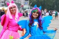 Two funny young girls  in blue and pink bright carnival dresses are smiling and walking along the street at the festival in Dnepr Royalty Free Stock Photo