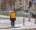 Courier with a yellow backpack delivers food to a client on foot