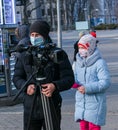 A girl resident of the city watches the work of a young videographer, a journalist outdoors