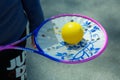 A man holds a tennis racket with a ball in his hand