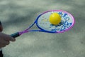 A man holds a tennis racket with a ball in his hand