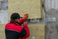 A man installs a layer of thermal insulation in the form of mineral wool panels. Cutting of