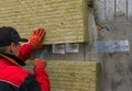 A man installs a layer of thermal insulation in the form of mineral wool panels. Cutting of