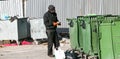 Homeless man searches for food and books in a dumpster. Selective focus, street photo,