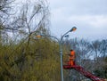 A municipal worker in protective gear replacing bulbs in a street lamp. A worker repairing a