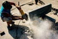 The process of laying sidewalk curb. A worker cuts a concrete block with a circular saw. A