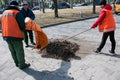 Two men and a woman collect old dry leaves in a spring park in a plastic bag. Municipal