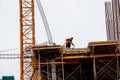 A worker prepares formwork for a modern metal-concrete structure of a residential building