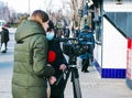 Young journalist and cameraman use a professional video camera to film news in the open air