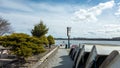 A lakeside scene with a row of overturned boats on a gravel path next to a waterbody. Evergreen shrubs Royalty Free Stock Photo