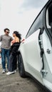 A couple stands beside an open car door, likely at a charging station. The car is white with modern design elements, featuring bla Royalty Free Stock Photo