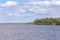 Dnipro river and green island under a cloudy blue sky on a sunny summer day