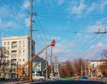 Electrician repairing wire of the power line with bucket hydraulic lifting platform on blue sky