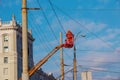 Electrician repairing wire of the power line with bucket hydraulic lifting platform on blue sky