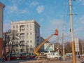 Electrician repairing wire of the power line with bucket hydraulic lifting platform on blue sky