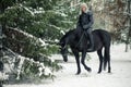 Cosplayer in image of a character Geralt of Rivia from the game or series The Witcher riding a horse winter forest Royalty Free Stock Photo