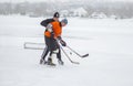 Young man fighting with mature man for the pack while playing hockey on a frozen river Dnipro in Ukraine