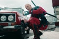 DNIPRO, UKRAINE - MARCH 28, 2019: Deadpool cosplayer posing with gun and katanas next to car