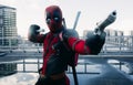 DNIPRO, UKRAINE - MARCH 28, 2019: Deadpool cosplayer posing with two guns and katanas against urban landscape