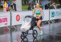 Young woman running with baby carriage during of the `Interipe Dnipro Half Marathon` race