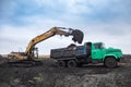 Dnipro, Ukraine - November 19, 2020: CAT crawler excavator at work. Loading raw materials into the car body.