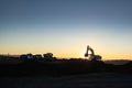 Dnipro, Ukraine - November 19, 2020: silhouette of Excavator loader at construction site with raised bucket over sunset.