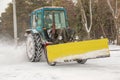 A worker on a tractor removes snow in the city park