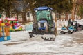 A worker on a tractor removes snow in the city park