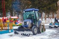 A worker on a tractor removes snow in the city park