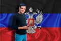 Dnr flag on the background of the texture. The young man smiles and holds a smartphone in his hand. The concept of design